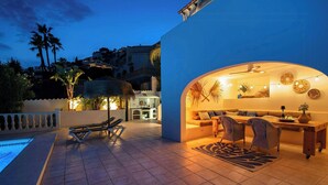 Un espacio exterior con piscina, sillas de descanso y zona de comedor.