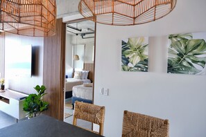 Une chambre moderne équipée d’un lit, d’un bureau et d’un coin repas avec des chaises en osier.