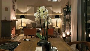 Ein Essbereich mit einem Holztisch, weißen Orchideen und drei großen, runden, weißen Pendelleuchten.