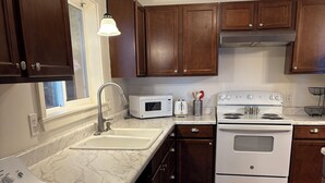 A kitchen with a built-in washer and dryer, a white stove, and wooden cabinets.