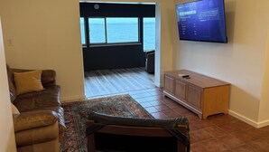 A living room with a sofa, a small cabinet, a television, and a view to the outside.
