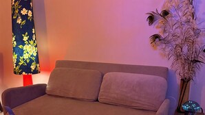 Ein Wohnzimmer mit einer Couch, einer Lampe, einem Blumentopf und einem dekorativen Gegenstand auf einem Tisch.