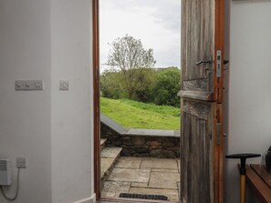 A doorway leading to a stone staircase and a grassy outdoor area with trees. - Lower Velwell Barn (Totnes)