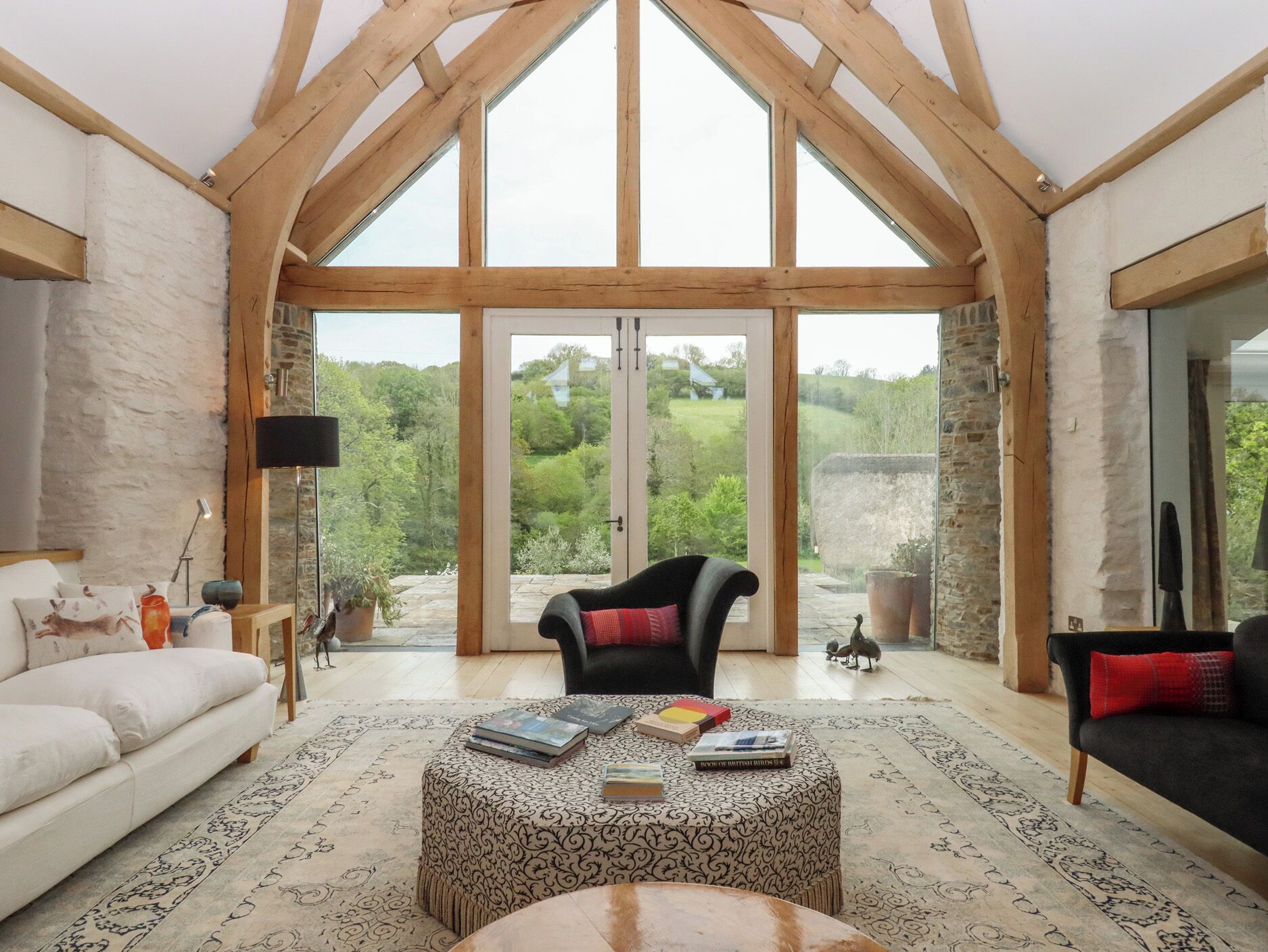 A spacious living room with a high ceiling, large windows, and a view of the outdoors.