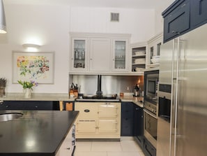 A modern kitchen with white cabinets, a stainless steel refrigerator, and a central island. - Lower Velwell Barn (Totnes)