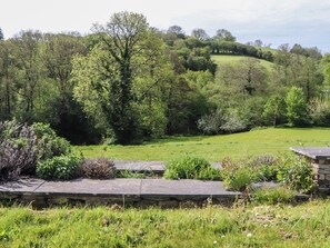 A grassy field with trees and a stone wall in the foreground. - Lower Velwell Barn (Totnes)