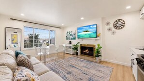 Una sala de estar moderna con sofá, televisión, chimenea y comedor.