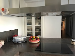 A modern kitchen with a built-in stove, a white cabinet with glass doors, and a bowl of fruit on the counter. - 🌿 House with swimming pool between Aix-en-Provence and Marseille - heart of Provence (Cabriès)