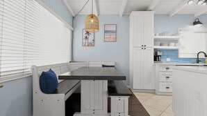A kitchen with white cabinetry, a wooden bench, and a hanging light fixture. - Blue Heron Perch - 5 minute walk to beach, garage (Newport Beach)