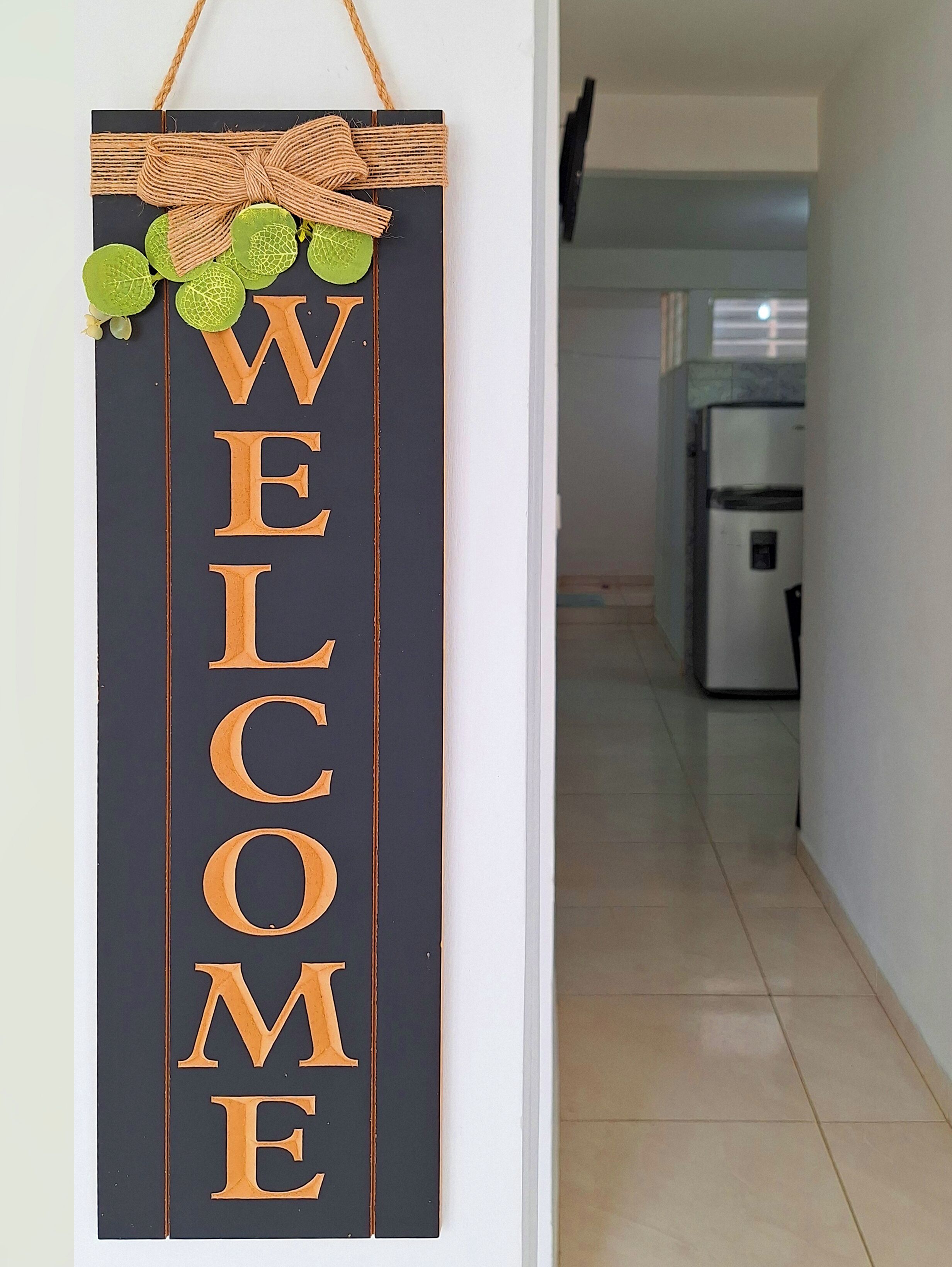 A vertical welcome sign with large letters and decorative elements.