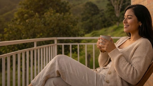 A person sitting on a wooden chair on a balcony with a view of a hilly landscape. - Cantabria Hospedaje (Popayán)