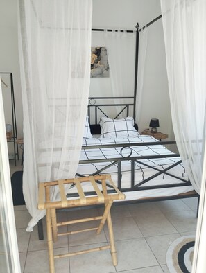 A four-poster bed with a canopy, a bedside table, and a lamp. - Athenian Riviera Suite ~Ano Voula (Athens)