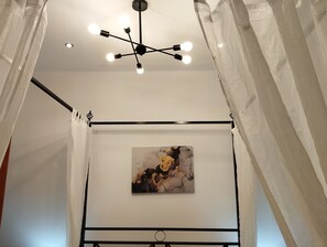 A room with a ceiling light fixture, a painting on the wall, and sheer curtains. - Athenian Riviera Suite ~Ano Voula (Athens)