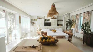 A spacious kitchen with a large island, a hanging thatched light fixture, and a view of the outdoors. - Centuries-old olive finca with pool in Cádiz (Barbate)