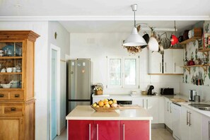 Eine Küche mit Kochinsel, Holzschränken, einem Kühlschrank und einer Pendelleuchte.