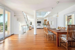 Ein modernes Interieur mit einem Holzespeisetisch, Stühlen, einer Treppe und einem großen Fenster.