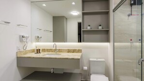 Een moderne badkamer met een wastafel, spiegel en douchecabine met glazen wanden.
