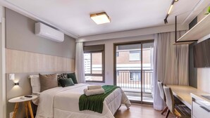 Een moderne hotelkamer met een bed, nachtkastje en een balkon met uitzicht.