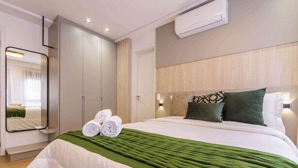 Een hotelkamer met een bed, een spiegel, een kledingkast en een airconditioning.