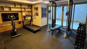 Een sportschool met een loopband, gewichtbank en losse gewichten.
