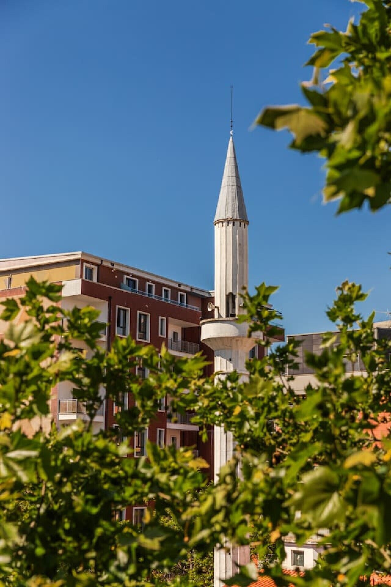 Ein Gebäude mit einem markanten Turm und einem flach gedeckten Bau im Vordergrund.