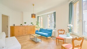 Een woonkamer met een bank, een salontafel, een houten kast en een raam met gordijnen.