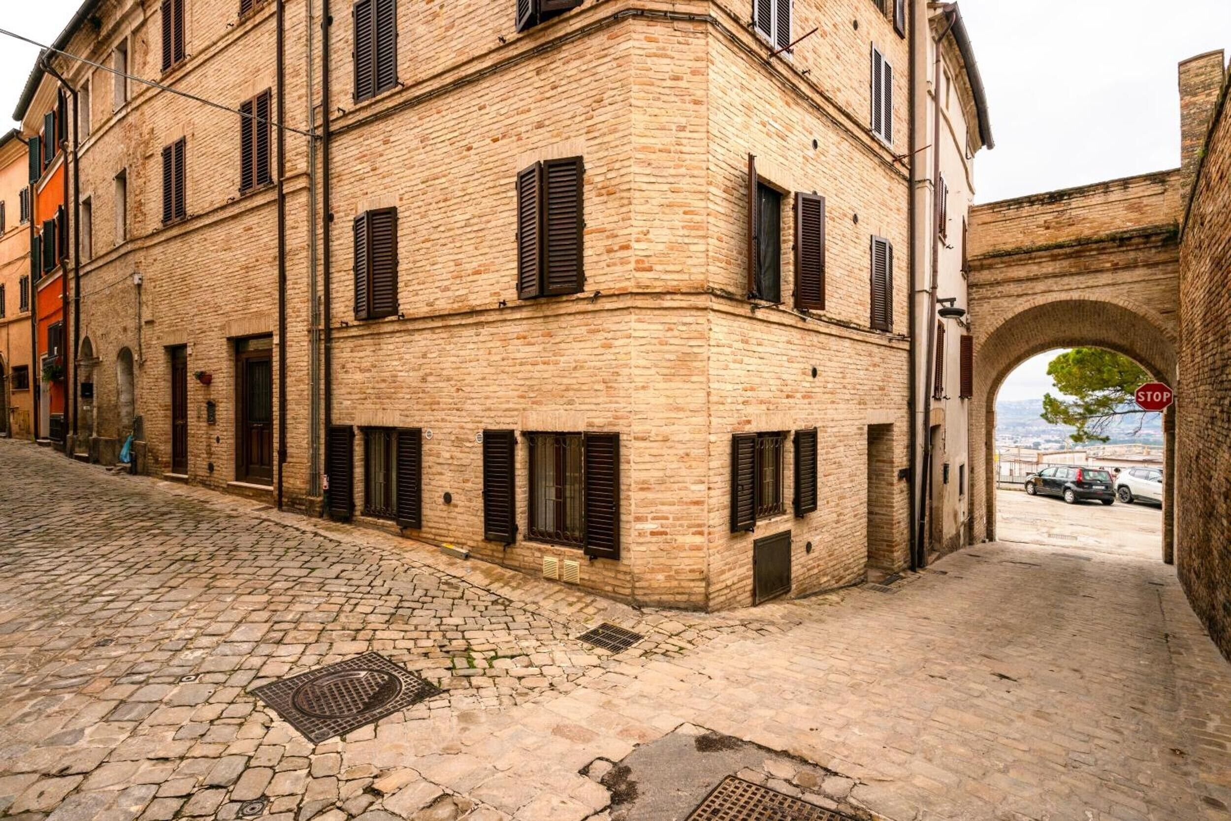 A cobblestone street with a brick building featuring multiple windows and shutters.