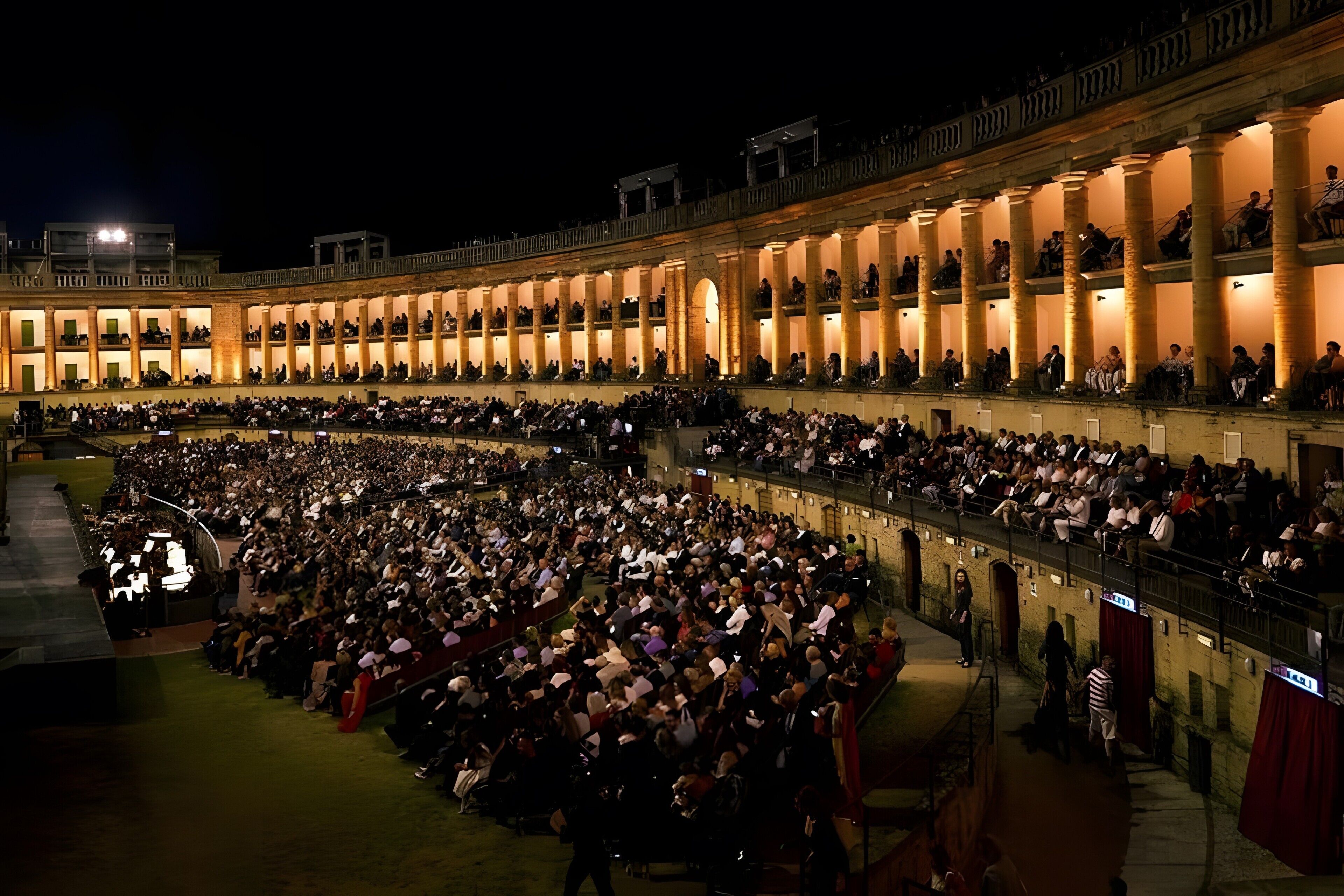 A large, open-air amphitheater with tiered seating and a central stage.