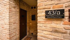 A stone wall with a door and a sign indicating '43/a Via Oberdan.' - Charming Apartment Maison all'arco (Corridonia)
