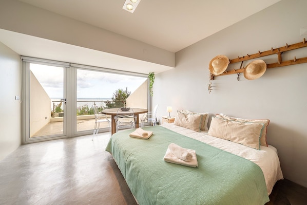 A bedroom with a bed, a balcony with a view, and a dining area.
