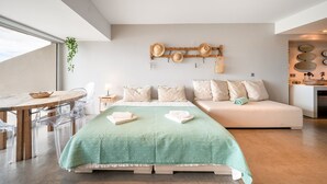Une chambre moderne comprenant un lit, un canapé, un coin repas avec des chaises et un porte-chapeaux fixé au mur.