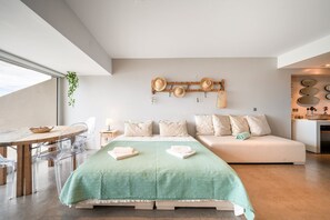 Une chambre moderne comprenant un lit, un canapé, un coin repas avec des chaises et un porte-chapeaux fixé au mur.
