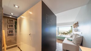 Un salon moderne avec un canapé, un coin repas avec une table et un balcon aménagé avec du mobilier d’extérieur.