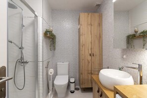 A modern bathroom with a glass-enclosed shower, a wooden wardrobe, a toilet, and a sink with a mirror. - Costa Caleta 1 - Two Bed (La Caleta)