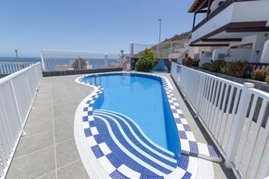 A swimming pool with a tiled edge, surrounded by white railings, and a view of the sea. - Costa Caleta 1 - Two Bed (La Caleta)