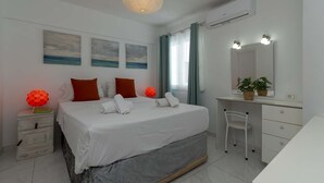 Un dormitorio con cama, mesitas de noche, escritorio, silla, espejo y obras de arte en la pared.