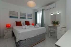 Ein Schlafzimmer mit einem Bett, Nachttischen, einem Schreibtisch, einem Sessel, einem Spiegel und Bildern an der Wand.