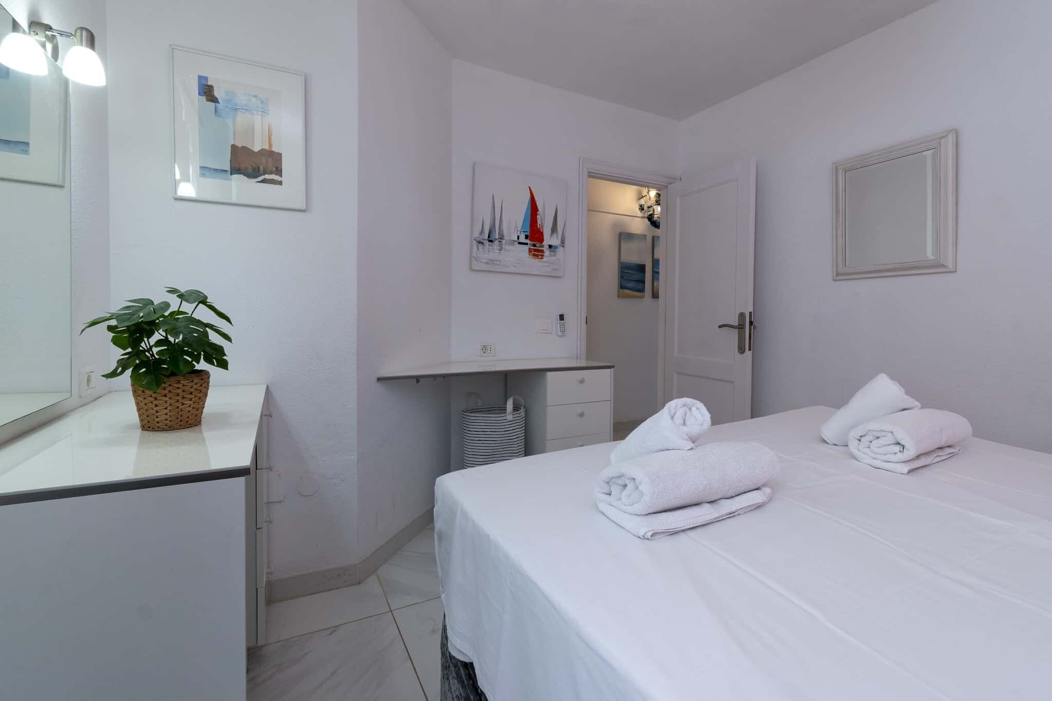 Une chambre d’hôtel avec un lit, une table de chevet, un miroir, une plante en pot et des œuvres d’art accrochées aux murs.