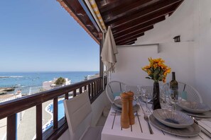 A balcony with a table set for dining, overlooking a coastal view with boats and a clear sky. - Costa Caleta 1 - Two Bed (La Caleta)