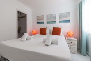 A hotel room with a large bed, two bedside tables, a wardrobe, and three paintings on the wall. - Costa Caleta 1 - Two Bed (La Caleta)