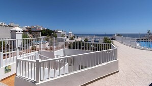 Terraza en la azotea con piscina, barandas blancas y una vista despejada del mar.