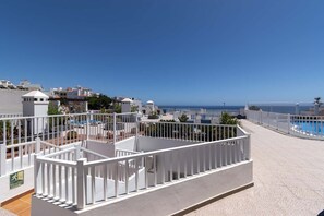 Eine Dachterrasse mit Pool, weißen Geländern und freiem Blick auf das Meer.