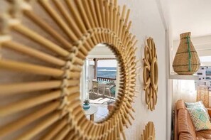 A sunburst mirror, wicker decor, a wicker vase, and a leather sofa with patterned cushions. - Costa Caleta 1 - Two Bed (La Caleta)