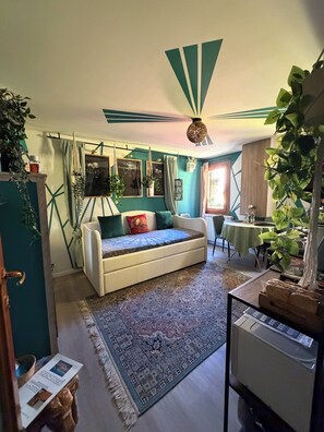 Un salon chaleureux avec un canapé, un tapis à motifs et un ventilateur de plafond.