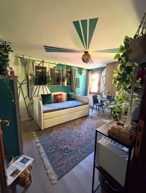 Een gezellige woonkamer met een bank, een kamerkleed met patroon en een plafondventilator.