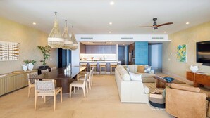 A modern living room with a dining area, kitchen, and a ceiling fan. - Costa Azul at Kupuri Beach Residences (Desarrollo Punta Mita)