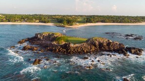 A coastal landscape with a rocky outcrop, a golf course, and a beach. - Costa Azul at Kupuri Beach Residences (Desarrollo Punta Mita)