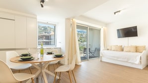 Un soggiorno moderno con zona pranzo, divano, TV a parete e vista sull'esterno.