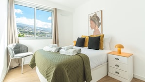 Una camera da letto con un letto, una sedia, un comodino, una lampada, un quadro e una finestra con vista.