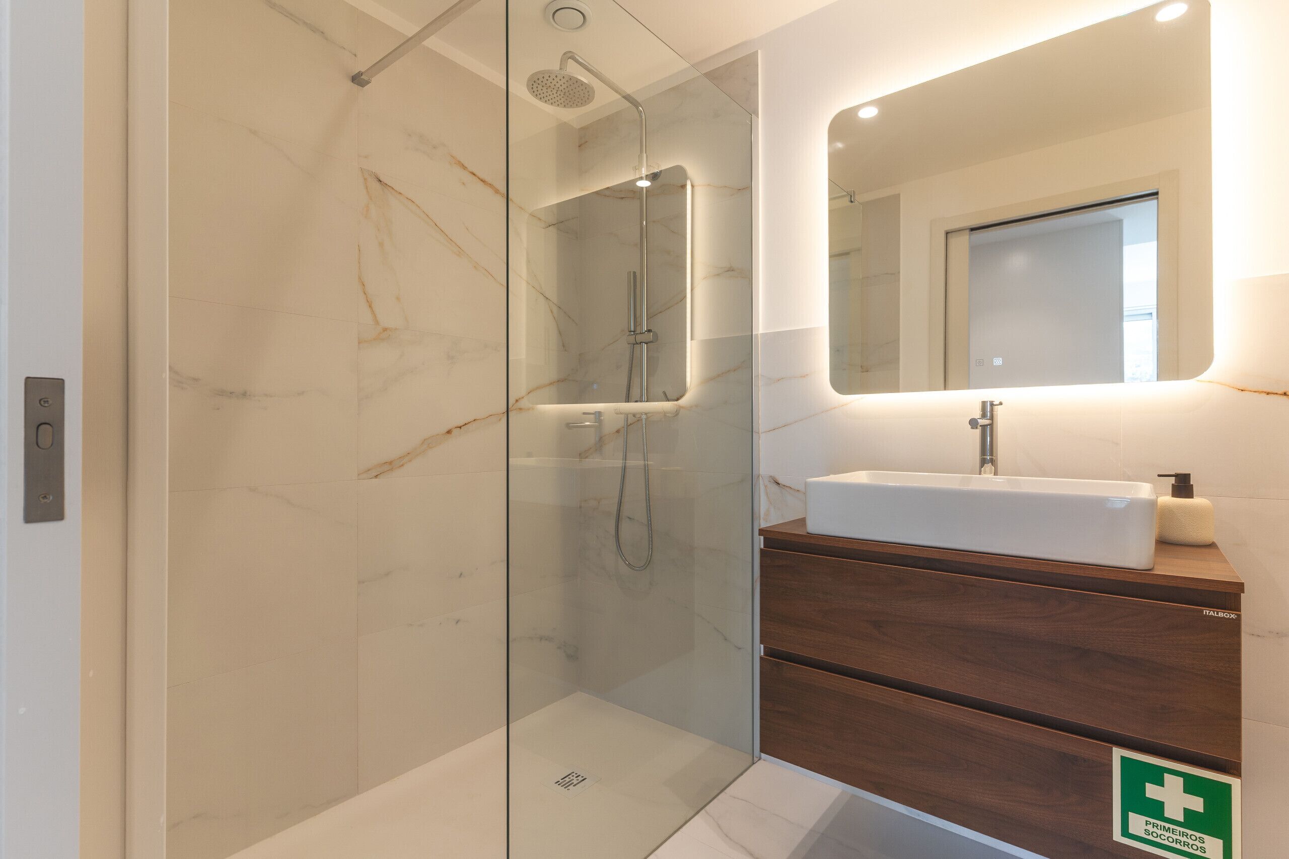 A modern bathroom with a glass-enclosed shower, a white sink, and a wooden vanity.